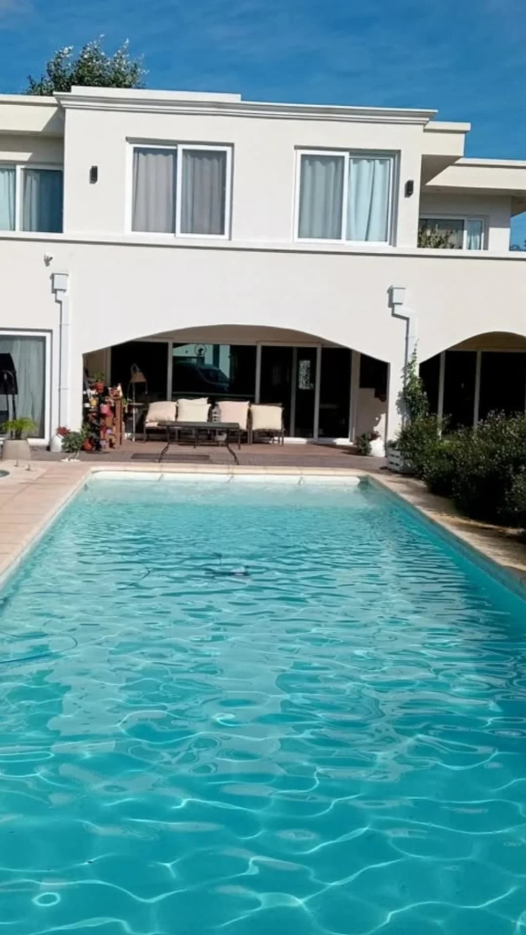 Gran piscina exterior con agua celeste frente a casa familiar